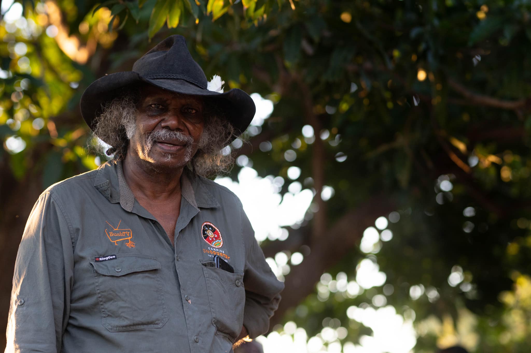 an Indigenous man in a black hat looks at the camera