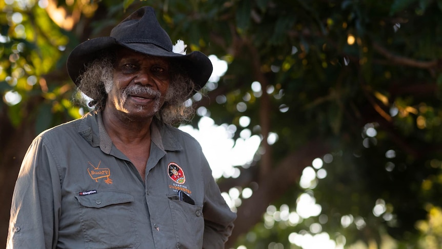 an Indigenous man in a black hat looks at the camera