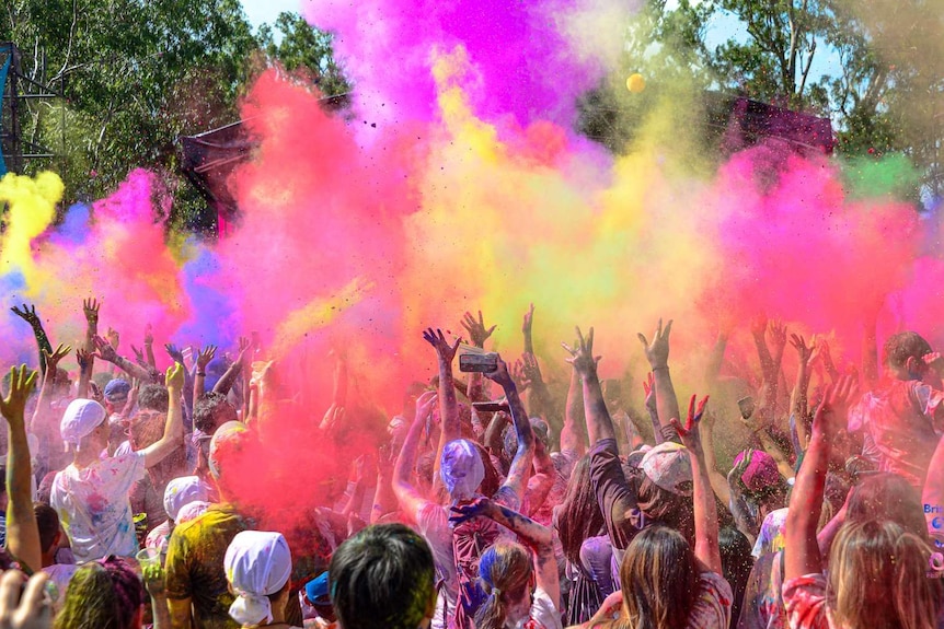 People dancing and covered in colourful powers.