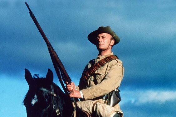 Actor Edward Woodward in military uniform on a horse holding a gun