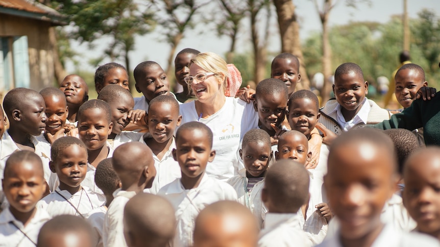 A blonde haired woman surrounded by African children