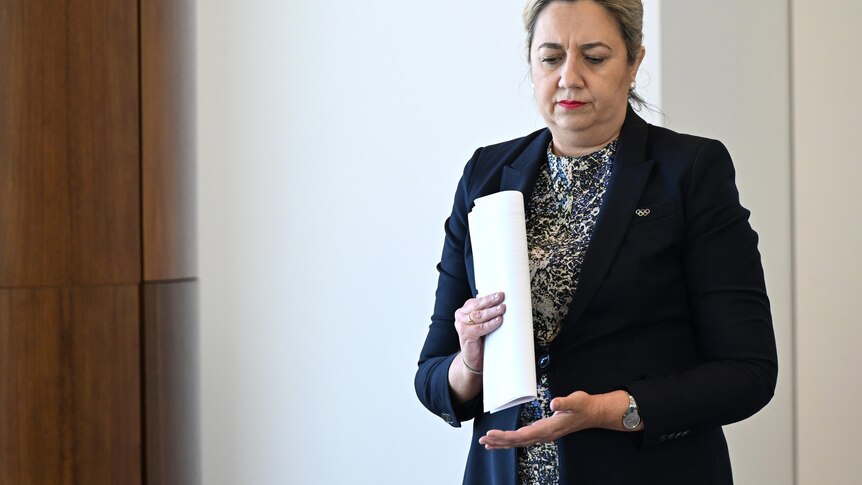 Palaszczuk holds report and looks down.