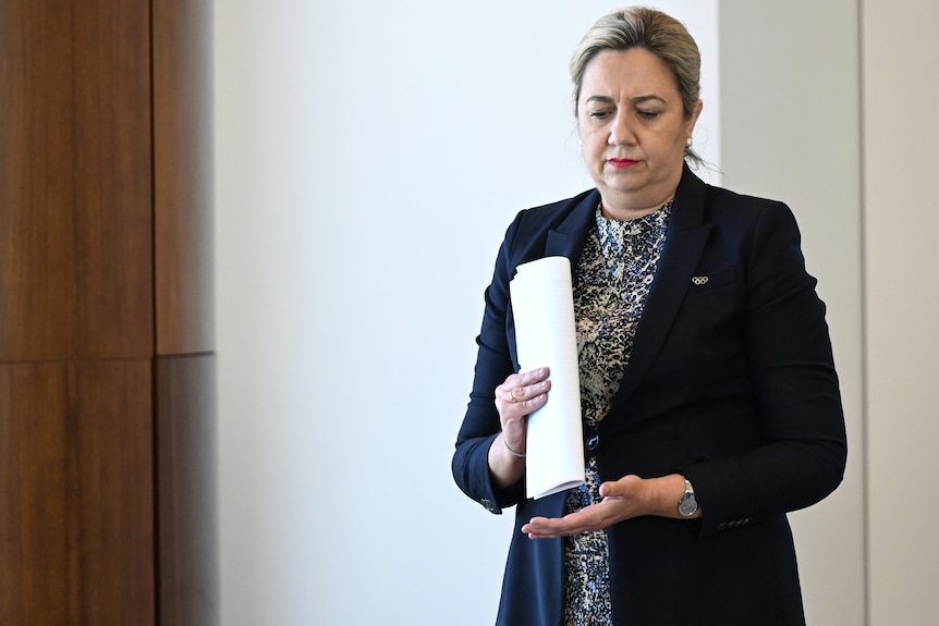 Palaszczuk holds report and looks down.