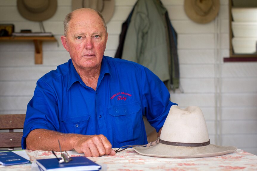 Grazier Toby Trebilco sits at a table covered with paper and his hat at his property at Hopeland.