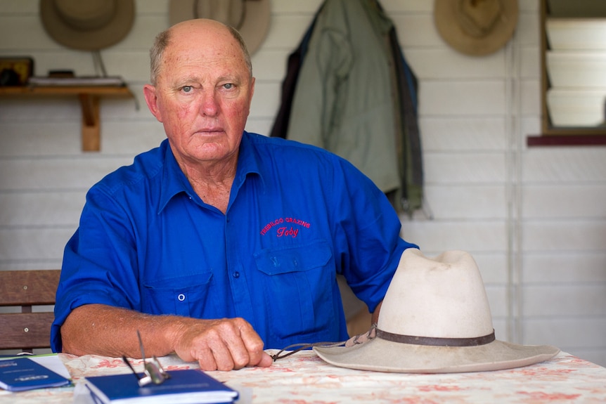 Grazier Toby Trebilco sits at a table covered with paper and his hat at his property at Hopeland.