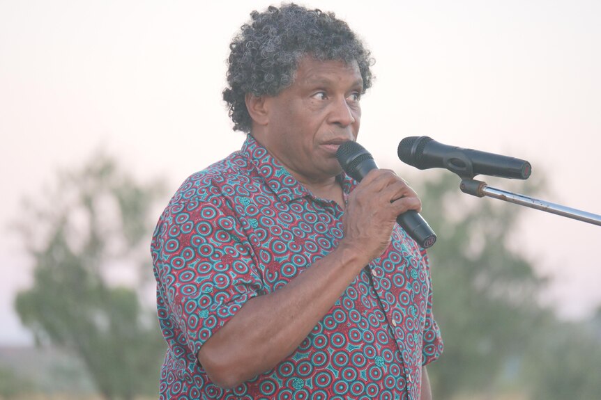 an Indigenous man speaks into a microphone