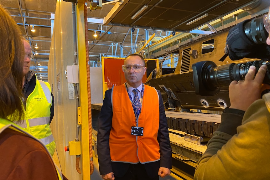 a man in a hi-vis vest stands inside a factory