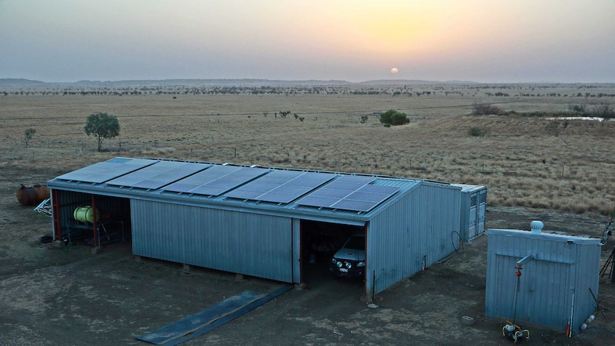 Aerial shot of solar panels on the roof of a shed at a cattle property at sunset