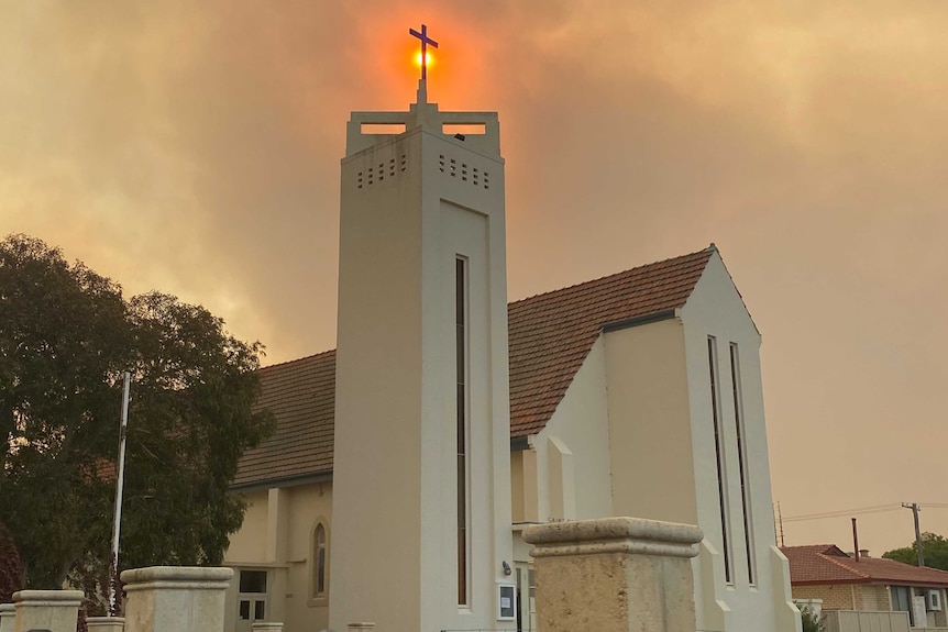 The sun is obscured behind black smoke and a church spire.