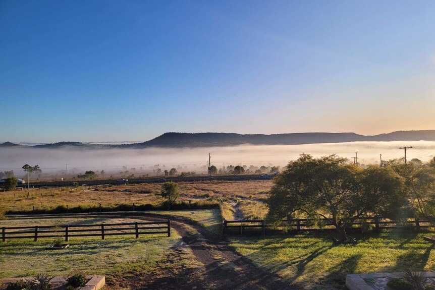 Fog and frost at Gowrie Mountain outside Toowoomba, green field, cloud above it and sun rising