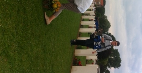 A child from Fromelles places a white rose at a newly named headstone.