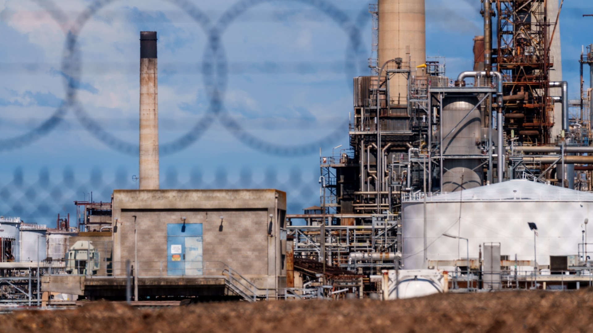 The Viva Energy oil refinery is seen through a barbed wire fence from the perimeter.