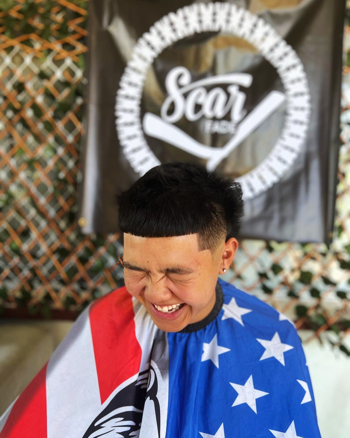 A young man laughs while getting a haircut
