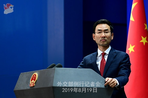 Geng Shuan at a press conference, standing in front of the Chinese flag