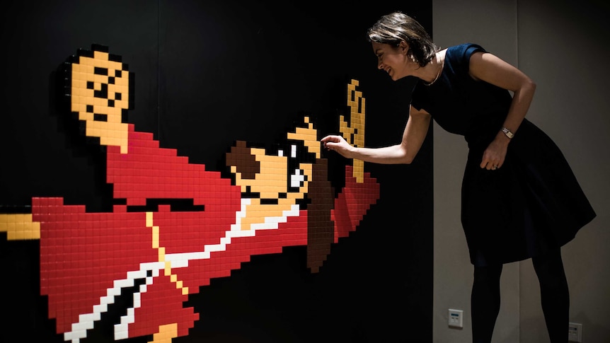 A Sotheby's employee touches a mosaic of Hong Kong Phooey.
