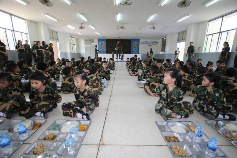 Children sit on floor with meal trays