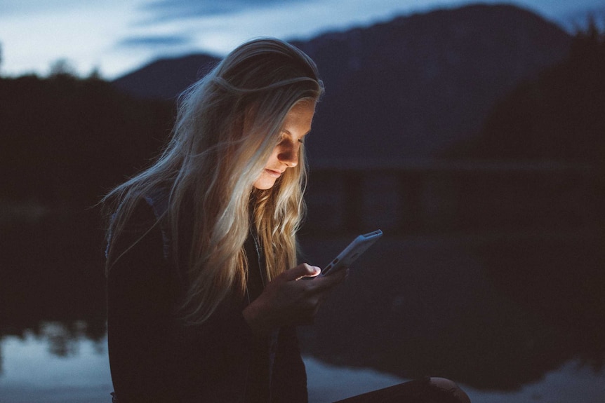 A woman's face is illuminated by her smart phone screen