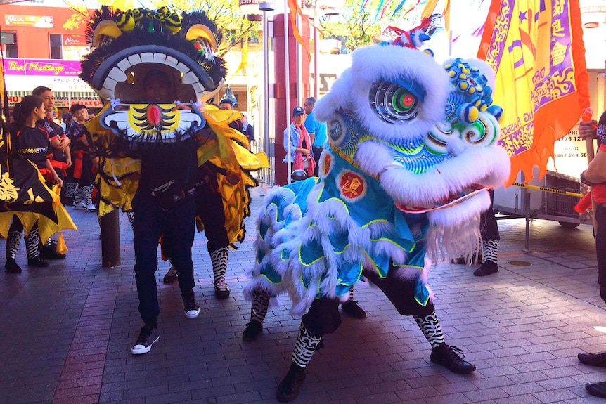 A blue dragon dances in the street.