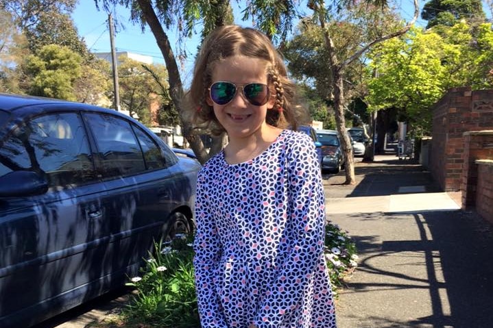 A child wearing a dress and smiling with hair plaited