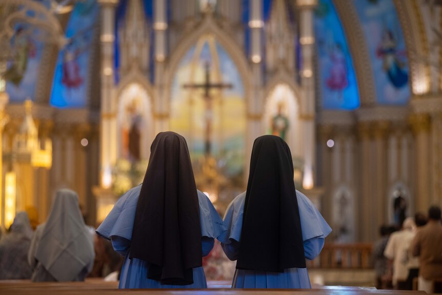 The picture is taken from behind, while the two nuns face the alter.
