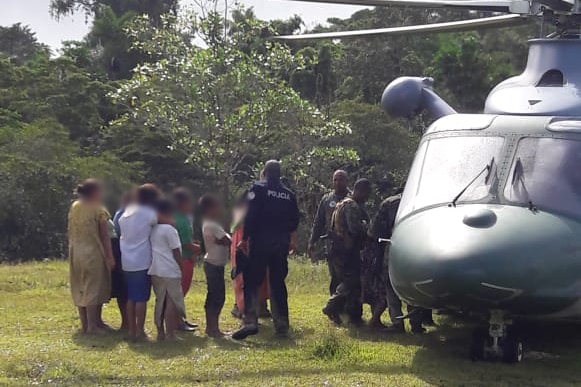 Police speak with people  near what appears to be a military chopper.