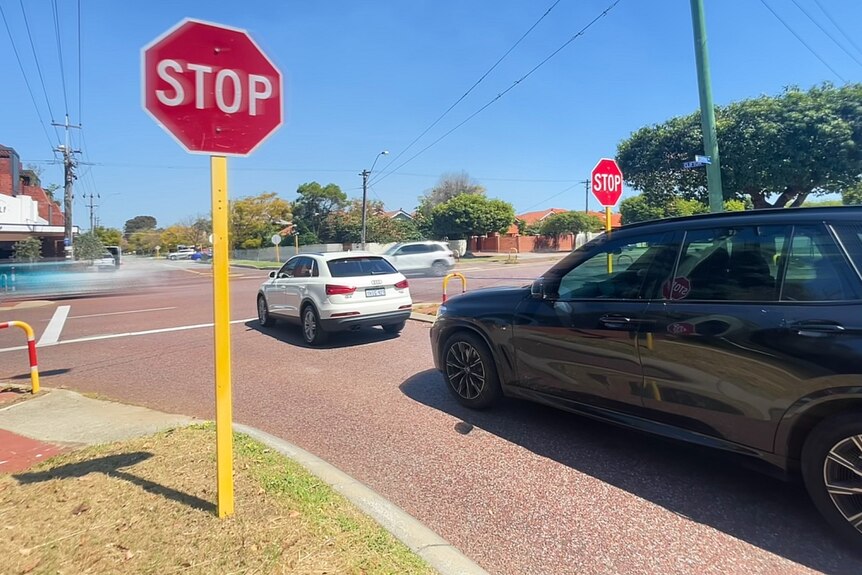 Cars stopped at a stop sign at a busy intersection