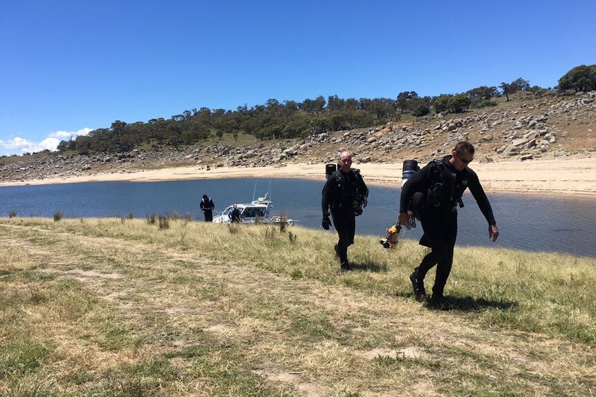 Police divers walk along the shore.