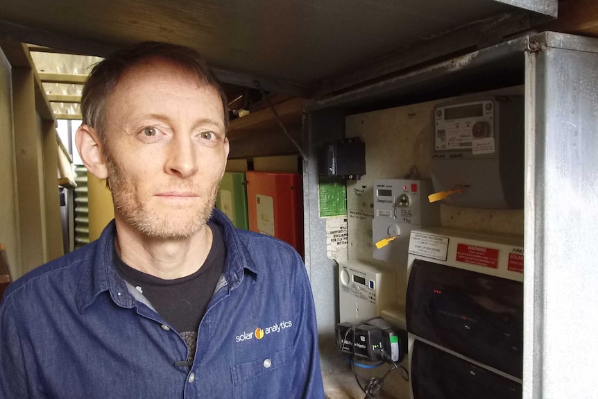 Man stands in front of an old power meter.