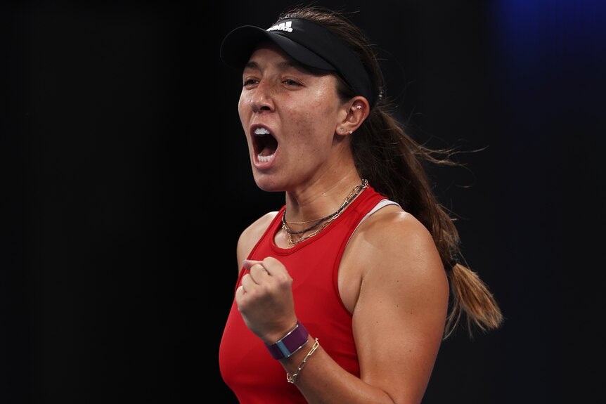 An American female professional tennis player pumps her left fist after winning a match.