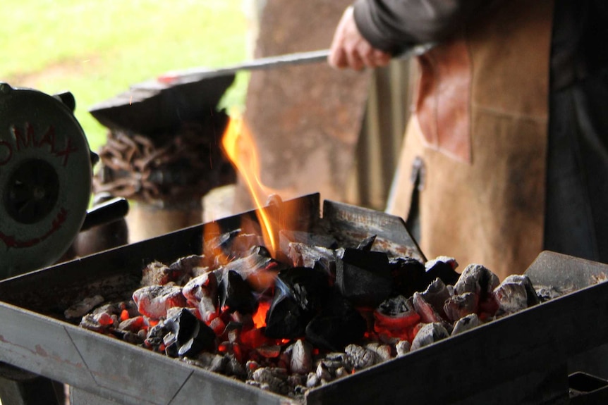 a large hammer hits a piece of hot steel with force