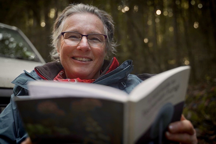 A woman sits outside reading a book.