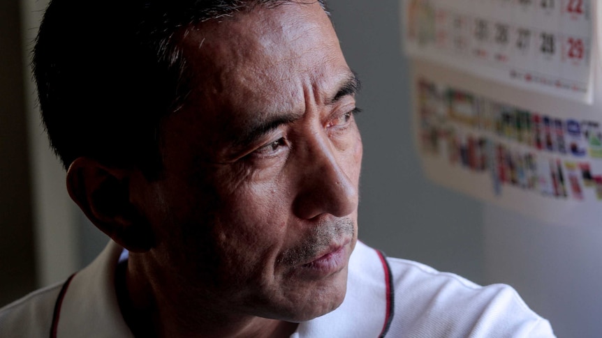 Man with black hair and white collared shirt stares to left of camera