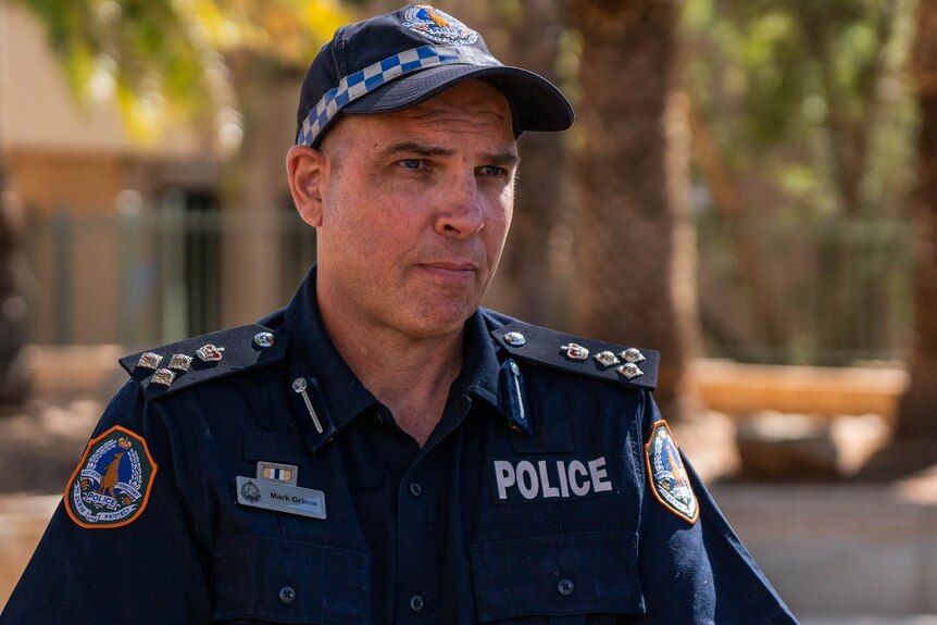A man in a NT Police uniform speaking to the media at a press conference, outside on a sunny day, 