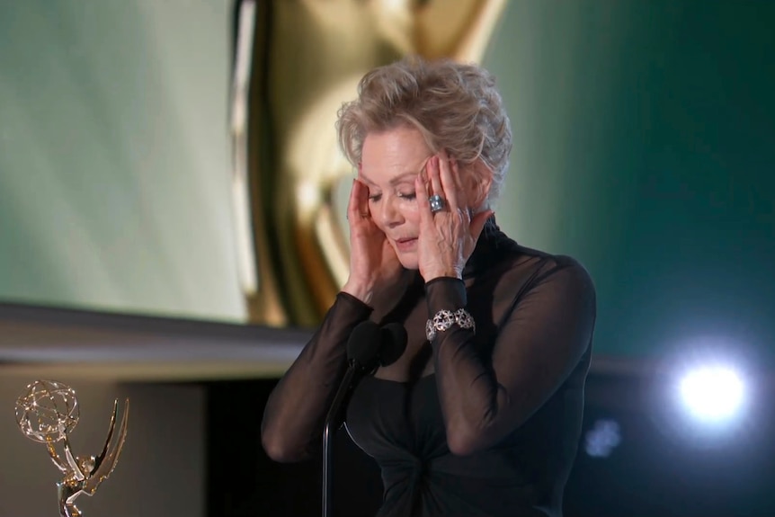 Jean Smart porte ses mains à son visage alors qu'elle accepte l'Emmy pour un titre exceptionnel dans une série comique.