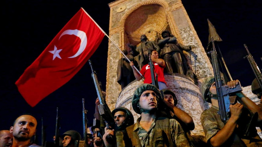 Demonstrators in Istanbul waving a Turkish flag and holding guns.