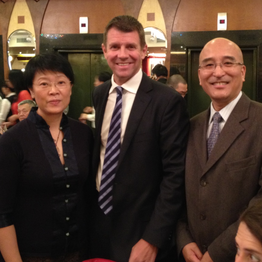 A woman and two men photographed at a restaurant.