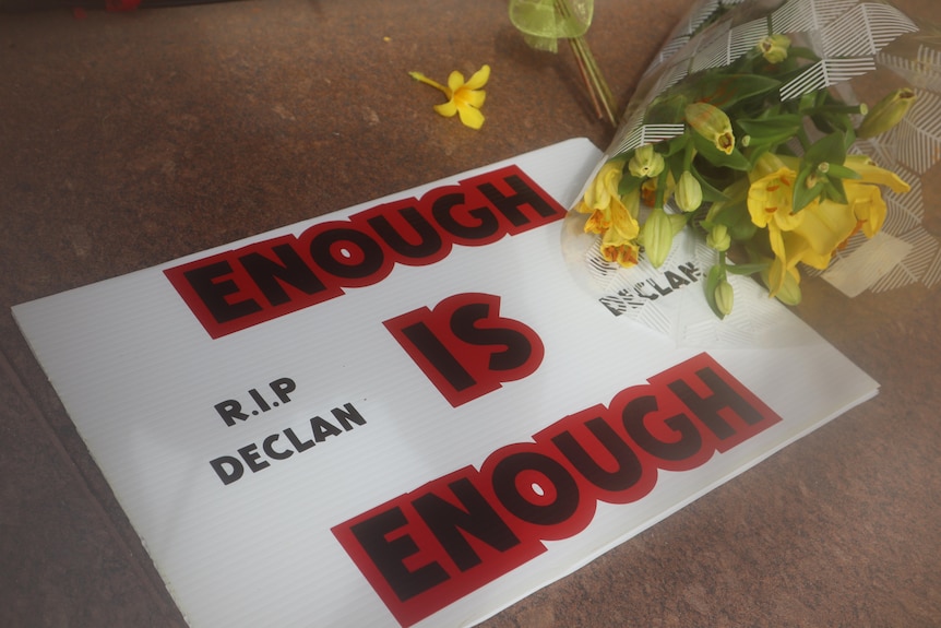 A sign reading 'Enough is Enough' left next to a bundle of flowers
