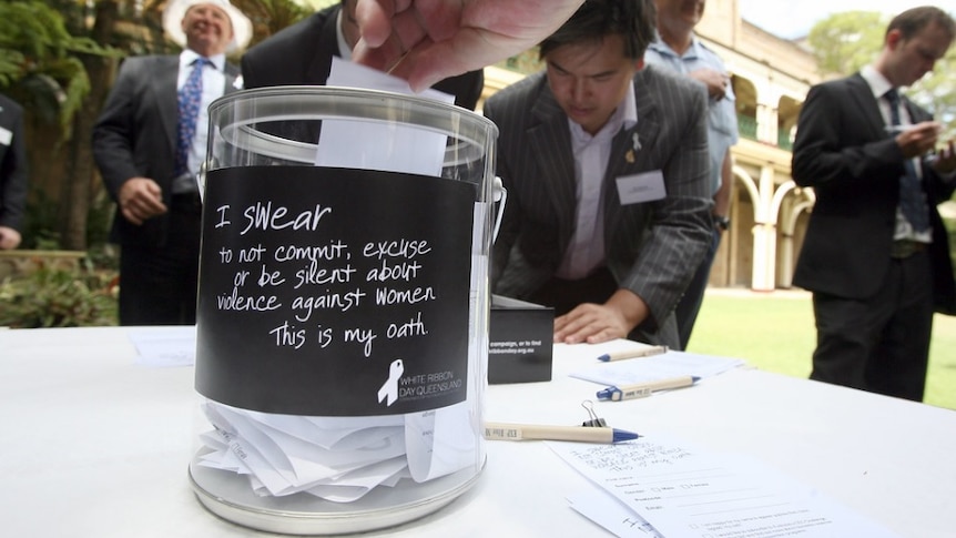 A man puts an oath into a swear jar vowing not to be silent against domestic violence.