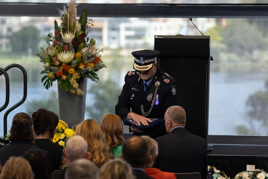 A police officer in full dress uniform at a funeral.