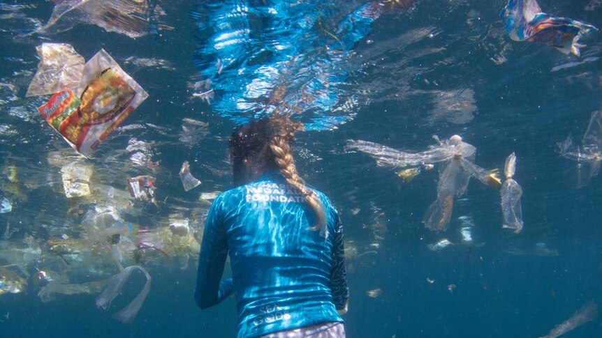 A snorkeler swims amongst the rubbish off Bali's coast.