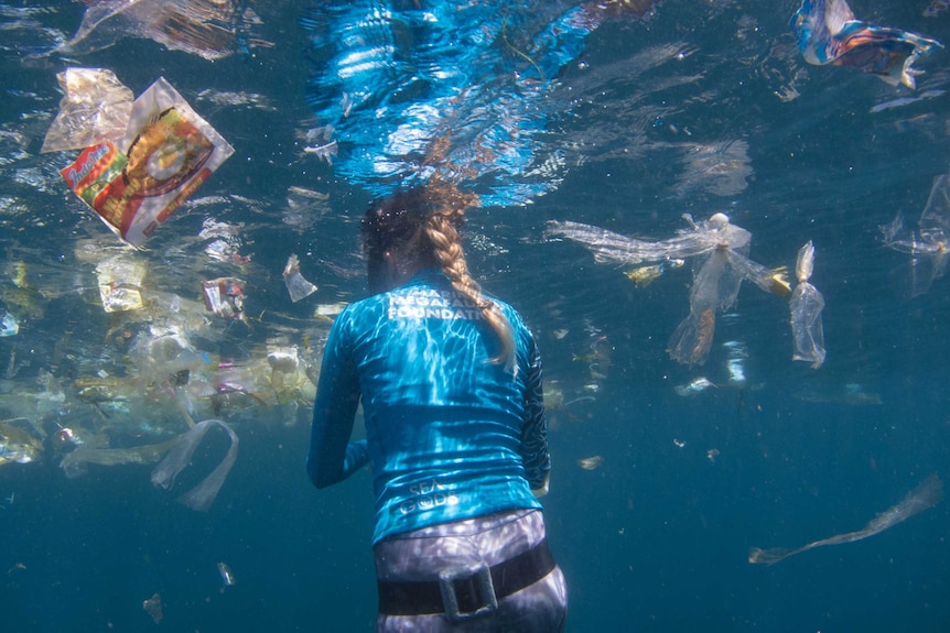 A snorkeler swims amongst the rubbish off Bali's coast.