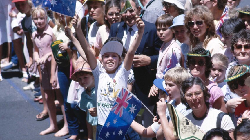 Children wave flags at the America's Cup victory celebrations in Perth