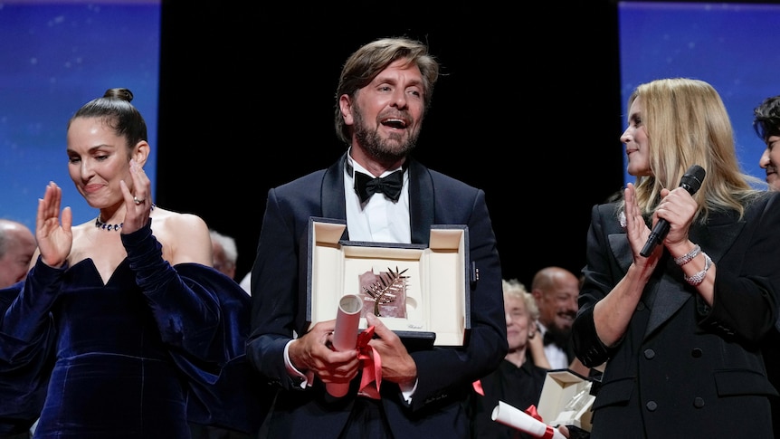 Ostlund stands on stage holding award smiling