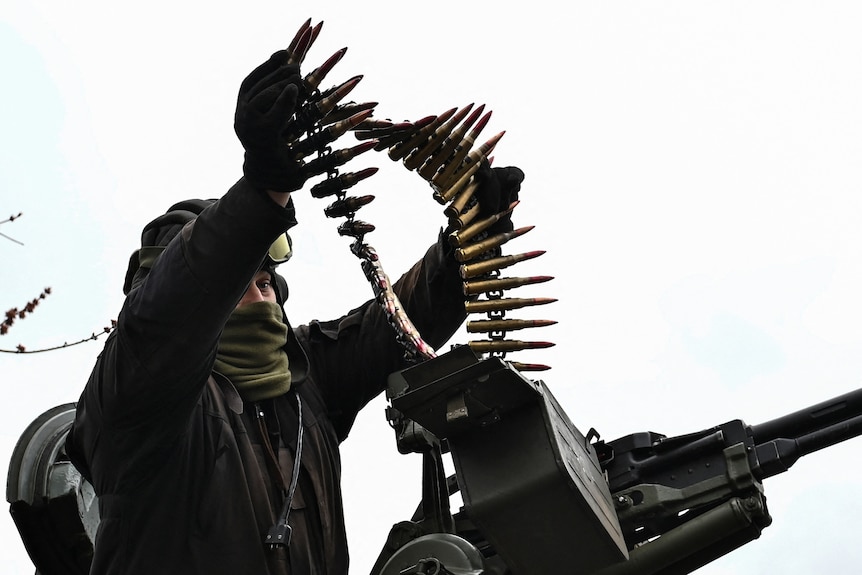 A Ukrainian serviceman loads ammunition for a machine gun.