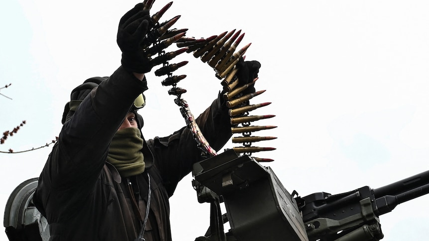 A Ukrainian serviceman loads ammunition for a machine gun.