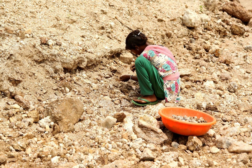 Gudiya, 13, breaks away pieces of mica from rocks in an illegal mine in India.