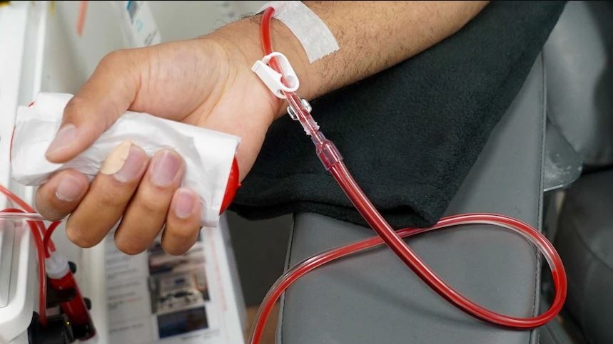 Close-up of a man's arm with blood donation equipment drawing blood