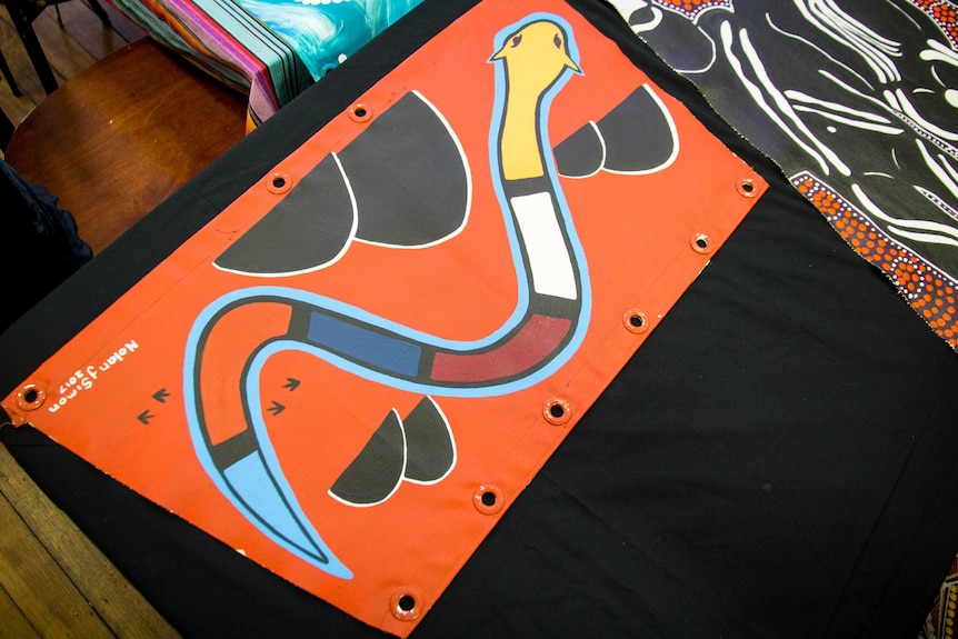 An orange coloured sail with a snake painted on it.