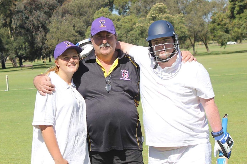 Crystal stands with her arm around her coach Wayne Hunt and batsman Jason Weir on the cricket ground.