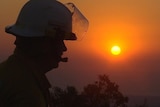 A silhouetted firefighter against the red sunset